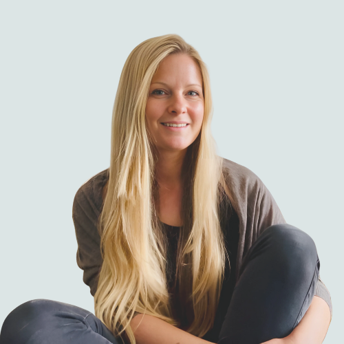 Inga Mehlhardt mit langen blonden Haaren, sitzt lächelnd mit angezogenen Beinen.